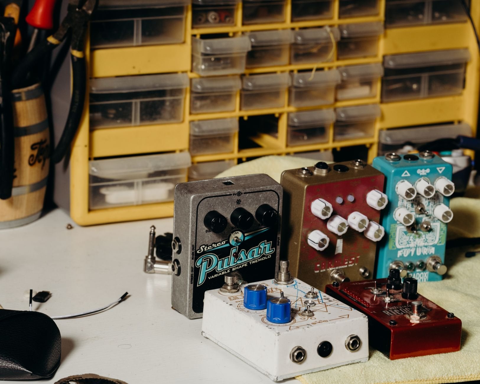 Close-up of various guitar effects pedals organized on a workbench.